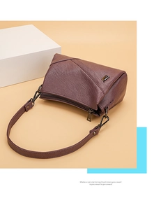 Détail du sac à bandoulière en cuir violet foncé avec texture litchi et double fermeture