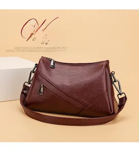 Détail du sac à bandoulière bordeaux avec texture cuir grainé et fermetures argent