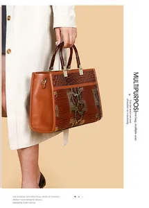 Details einer braunen Henkeltasche mit Krokodilprägung und goldenen Metallschnallen
