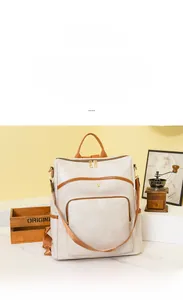 Detail of a minimalist beige faux leather backpack with brown contrast edge and gold zippers