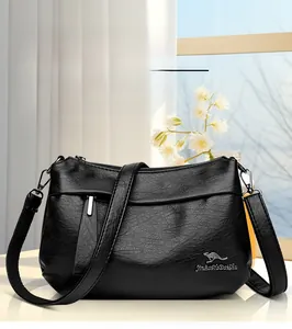 Détail du sac à bandoulière en cuir noir avec logo kangourou métallique élégant