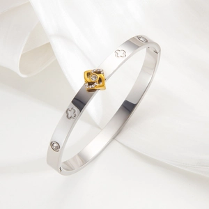Polished silver stainless steel clover bracelet with a gold diamond-encrusted pendant