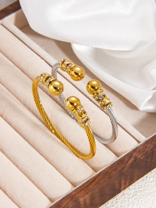 Detail of twisted cable bangles with crystal-set crossover rings in 18k gold and silver