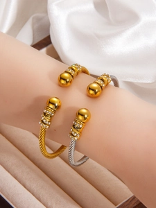 Detail of twisted cable cuff bracelets in gold and silver finish with crystal ball ends