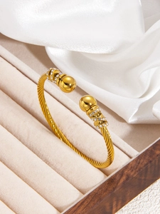 Detail of gold twisted cable cuff bracelet with crystal encrusted spherical ends