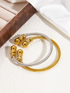 Detail of gold and silver cable bracelets with crystal encrusted spherical ends on silk