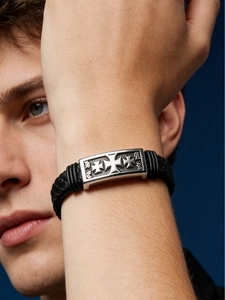 Detail of men's black braided leather bracelet with gothic cross silver metal buckle