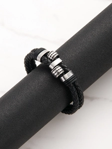 Macro detail of braided black leather bracelet with textured silver metal beads on display