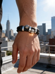 Men's braided black leather bracelet with polished silver charms shown on a wrist