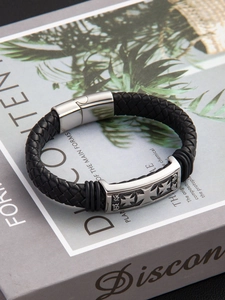 Detail of gothic cross engraving and leather weave on vintage punk magnetic bracelet