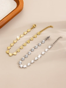 Macro view of gold and silver heart-shaped link bracelets with radiant texture on satin