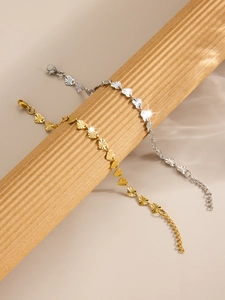 Macro shot of 18k gold and silver heart-shaped link bracelets with textured finishes