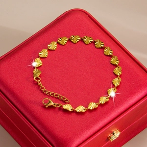 Golden heart-shaped titanium steel bracelet with sunburst texture on a red jewelry box