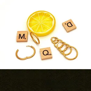 Various sizes of gold stainless steel hoop earrings displayed with stylized props