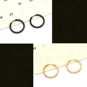 Close-up of black and gold stainless steel hoop earrings with polished finish and hinges