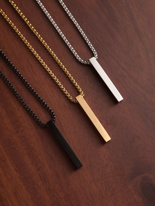 Detailed view of square bar pendants in silver, gold, and black on a wooden surface