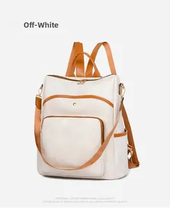 Detail of white Oxford fabric backpack with brown straps and golden metal hardware