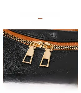 Close-up of golden dual zippers and lychee grain leather texture on a black backpack