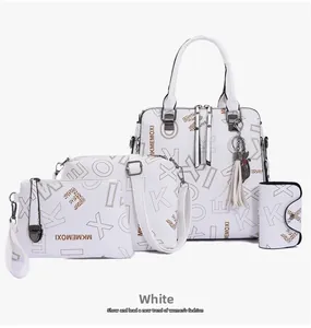 Detail showing white four-piece handbag set with printed monogram and tassel ornament