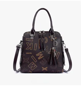 Detail of printed tote bag featuring metallic cat pendant, tassels and dual zip closure