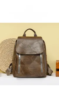 Detail of vintage brown patchwork backpack with decorative metal zippers on leather texture