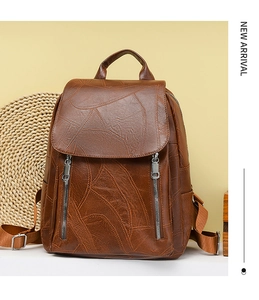 Close-up of vintage brown leather backpack with embossed leaf texture and dual zippers