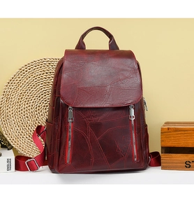 Detail of burgundy patchwork leather backpack with silver zippers and textured surface