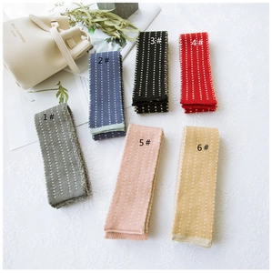 Close-up of narrow striped knit scarves in six colors including grey, blue, and red