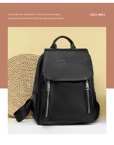 Detail of leaf-embossed flap and vertical silver zippers on black leather backpack
