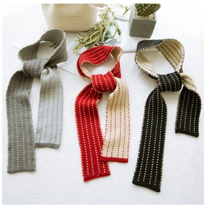 Detailed knit texture of slim striped scarves in grey, red, and black on a white surface