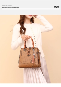 Detail view of brown textured PU leather tote bag with stylish charms and metal hardware