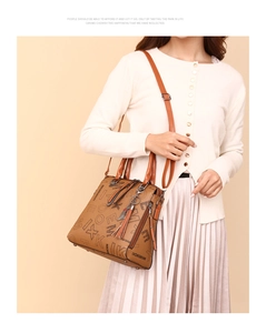 Close-up of brown printed crossbody bag with tassel detail on an Asian model
