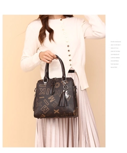 Detail of dark brown leather tote with letter prints and cat charm shown on model