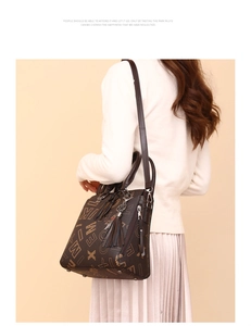 Detail of dark brown faux leather tote bag with letter patterns and tassel charm