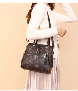 Detail of vintage brown monogram handbag with adjustable strap and metal hardware