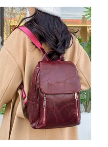 Detail view of burgundy faux leather backpack with vintage texture and zipper accents