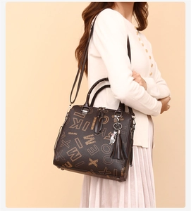 Detail of printed tote bag with adjustable strap and decorative cat charm and tassel