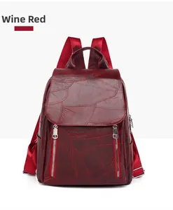 Detail of wine red faux leather backpack showing leaf vein texture and silver zippers