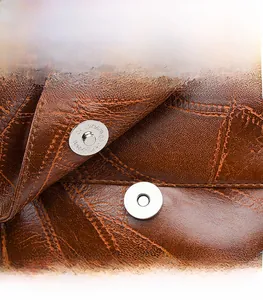 Detail of magnetic snap closure on vintage brown leather backpack with neat stitching