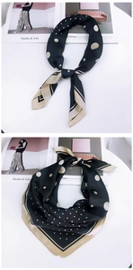 Détails d'un foulard en soie à pois noirs et crème avec une bordure dorée élégante