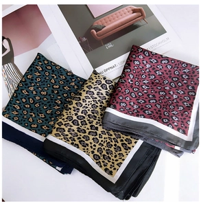 Detailed view of leopard print square scarves in green, yellow, and red silk fabric