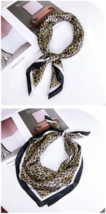 Macro shot of leopard print silk scarf with contrast striped borders on magazine
