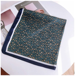 Detail of vintage leopard print square silk scarf with navy blue borders on white table