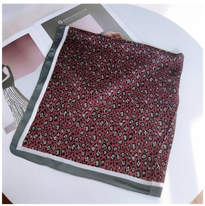 Flat lay of vintage leopard print square silk scarf on a white decorative platform