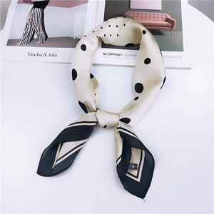 Foulard chic en soie beige à pois noirs avec bordure contrastée posé sur des magazines