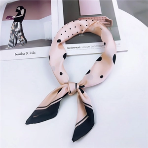 Foulard chic en soie rose à pois noirs avec bordure contrastée sur une table minimaliste