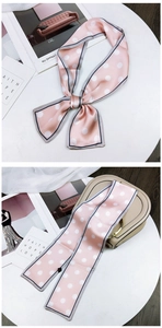Pink polka dot silk scarf tied on a handbag handle and styled as a decorative bow knot