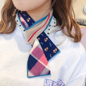 Detail of a thin silk twilly scarf showing a mix of cat prints, plaids, and polka dots