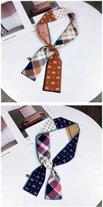 Detail of silk-feel scarf with cat pattern, polka dots and plaid on white table