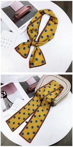 Close-up of yellow polka dot silk scarf tied on a handbag with smooth satin texture